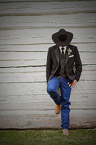A man wearing black jeans, cowboy boots, and a cowboy hat