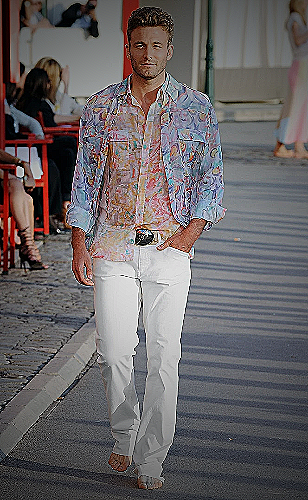 A man wearing white pants and a floral shirt, standing next to a palm tree - how to wear white pants men